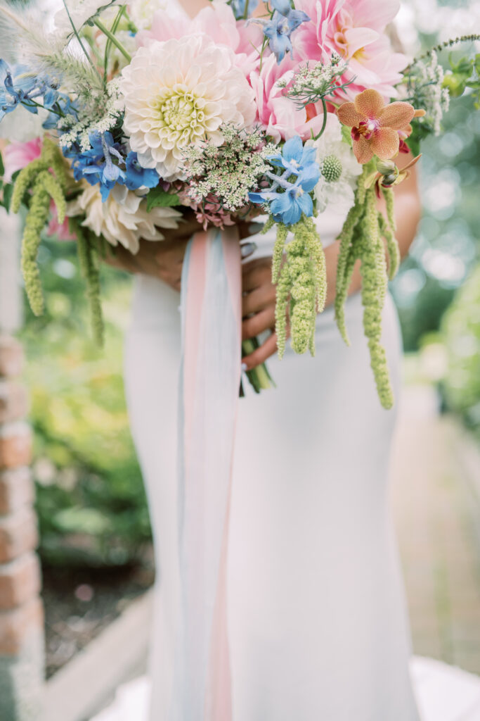 Bride holding a loose seasonal wedding bouquet with trailing amaranthus and soft summer flowers