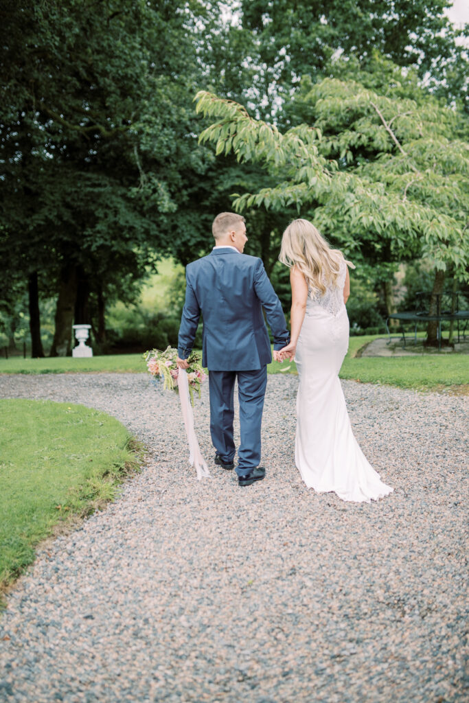 Couple walking through the grounds at Corick House Hotel with seasonal wedding flowers
